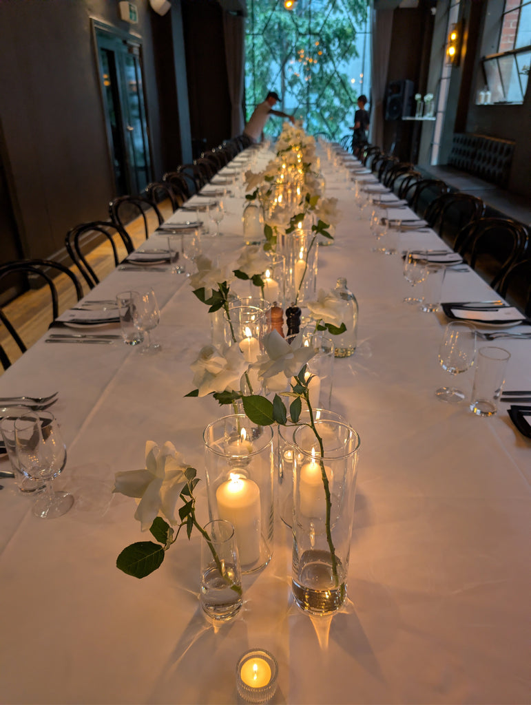 table setting of budvases and candle light for wedding long table
