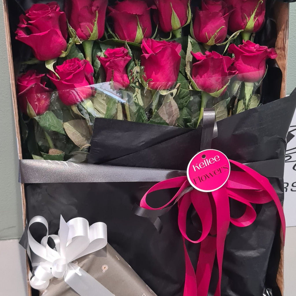 Bouquet of red roses with a gift and pink ribbon in a box